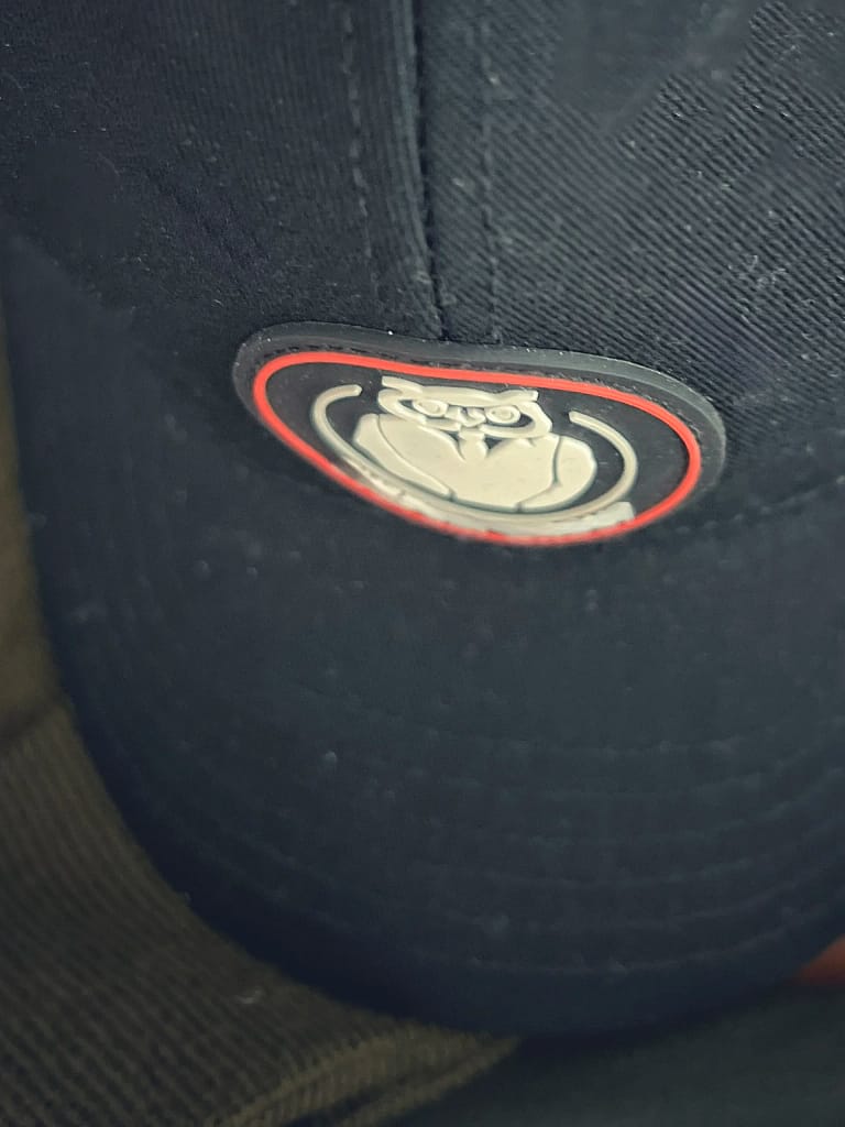 APPLICAZIONE ETICCHETTA PATCH IN GOMMA CON SCRITE E LOGO A RILIEVO SU CAPPELLO